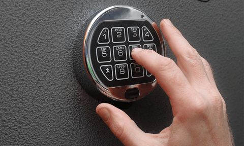 A hand entering the combination using the keypad on a gun safe